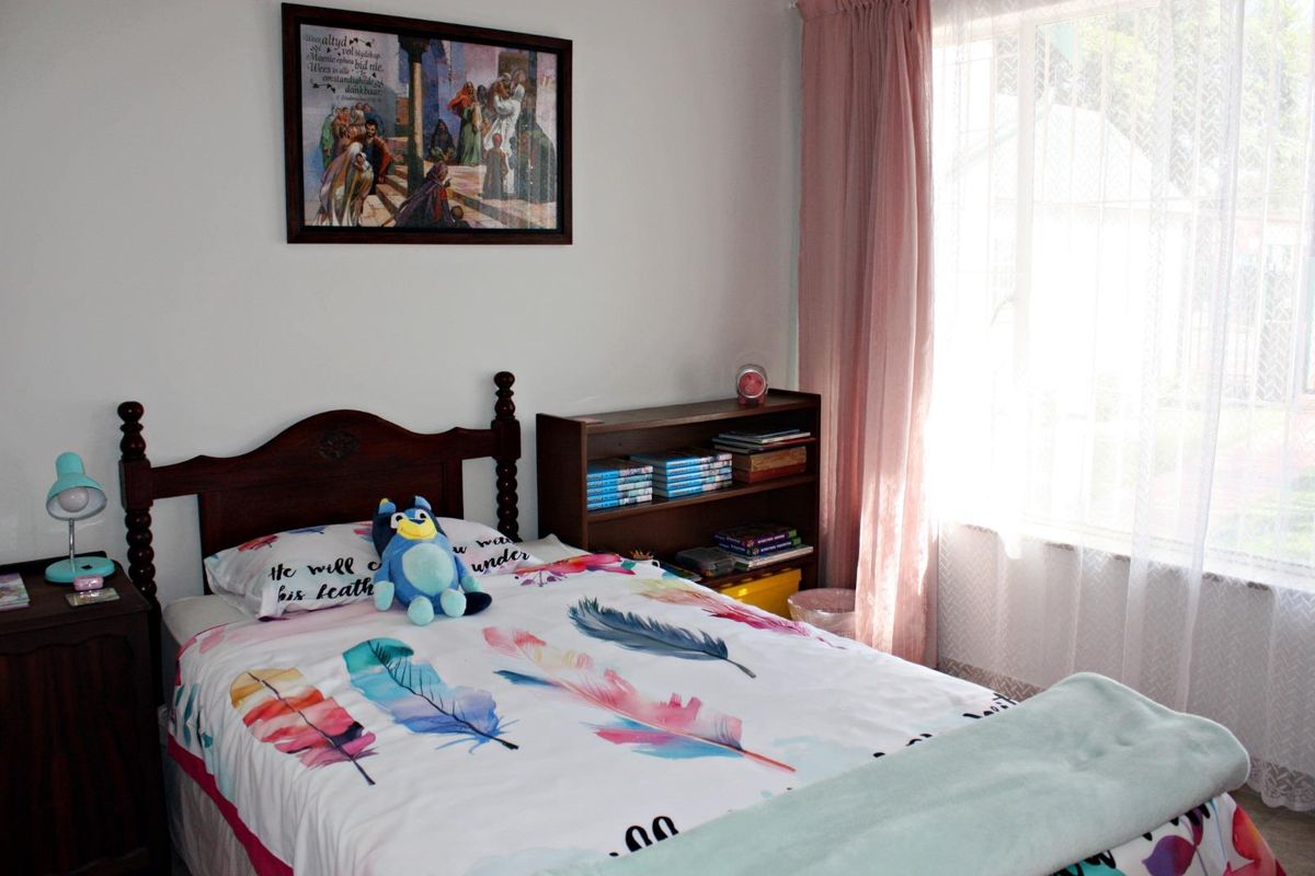 A cozy bedroom featuring a window with natural light, neutral walls, and standard flooring.