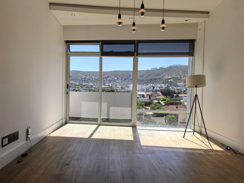 Bright and spacious living area featuring large sliding glass doors with expansive mountain and city views, modern laminate flooring, and contemporary lighting fixtures.