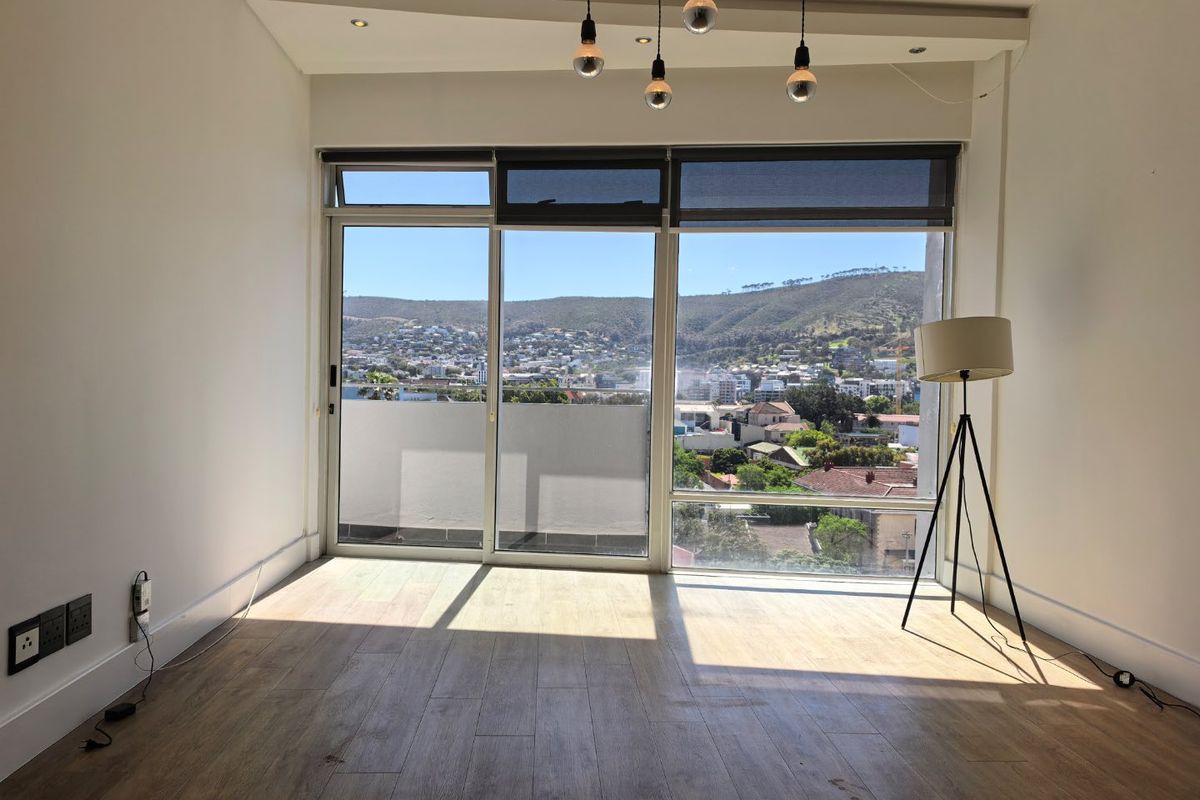 Bright and spacious living area featuring large sliding glass doors with expansive mountain and city views, modern laminate flooring, and contemporary lighting fixtures.