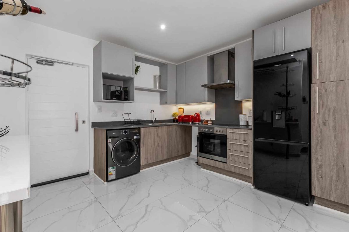 Modern kitchen featuring sleek two-tone cabinetry, stone countertops, integrated appliances, and high-gloss marble-look floor tiles.
