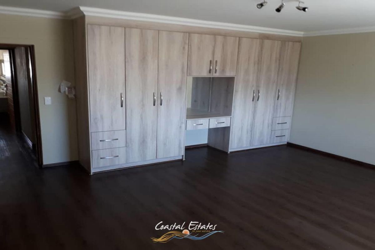 Spacious bedroom featuring extensive built-in cabinetry with integrated vanity and dark wood-look flooring.
