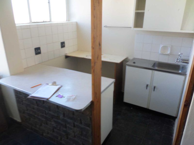 A functional scullery or utility area featuring a stainless steel sink, tiled splashbacks, and built-in cabinetry with laminate countertops.