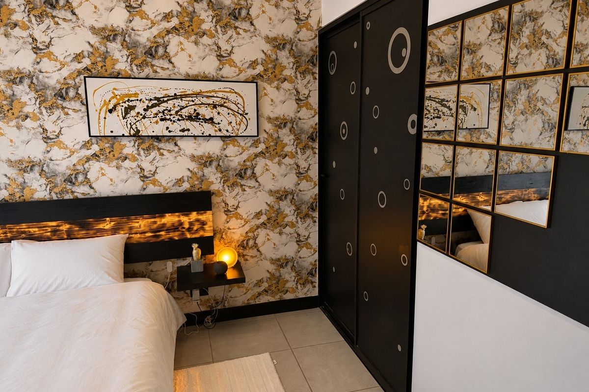 A modern bedroom featuring bold marble-patterned wallpaper, tiled flooring, and a sleek black built-in wardrobe with decorative circular accents.