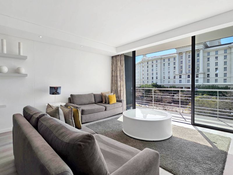 Bright living room featuring large sliding glass doors leading to a balcony with urban views and modern recessed ceiling lighting.