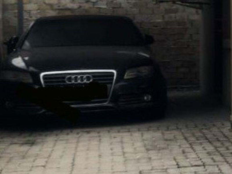 A covered parking area or garage space featuring stone wall cladding and paved flooring.