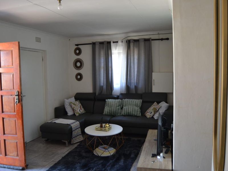 A compact living room featuring tiled flooring and a wooden panel door, providing a functional and accessible space.