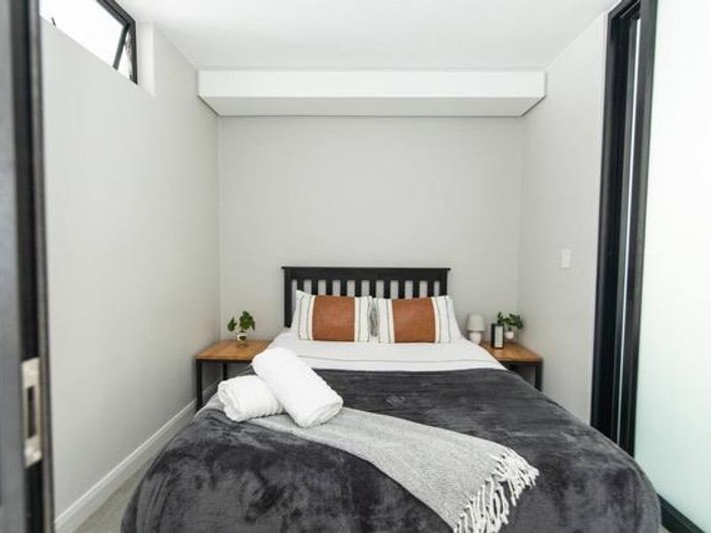 A modern, compact bedroom featuring clean lines, a recessed ceiling bulkhead, and a clerestory window for natural light.
