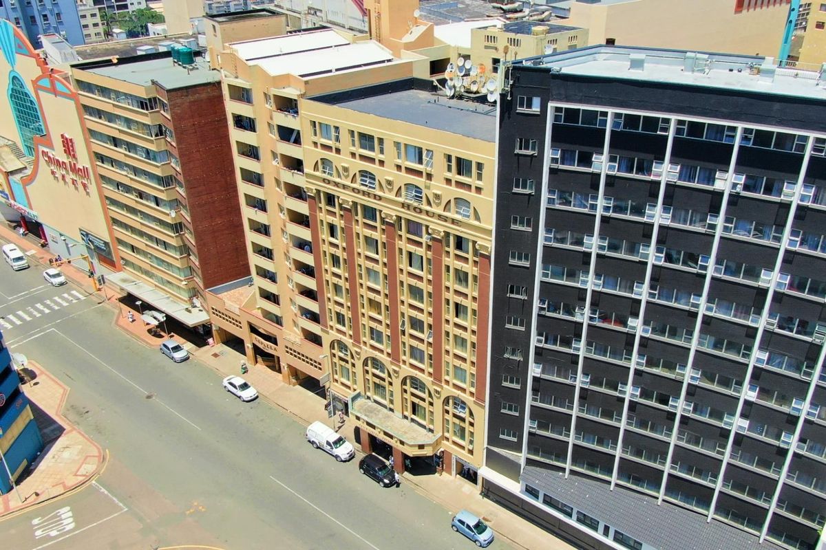 An aerial view of a city street featuring the Oxford House apartment building and surrounding urban infrastructure.