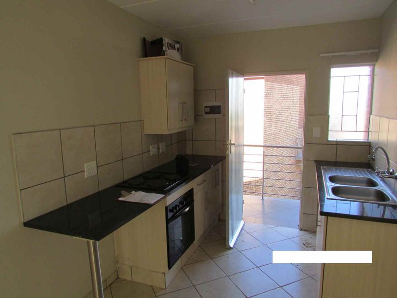 Functional kitchen featuring built-in cabinetry, granite countertops, a double bowl sink, and an integrated oven with hob, leading out to a balcony.