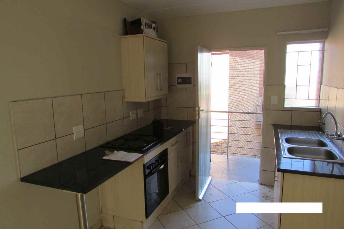 Functional kitchen featuring built-in cabinetry, granite countertops, a double bowl sink, and an integrated oven with hob, leading out to a balcony.