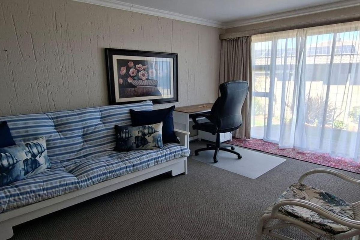 A living room featuring textured walls, carpeted flooring, and a large sliding glass door providing natural light.