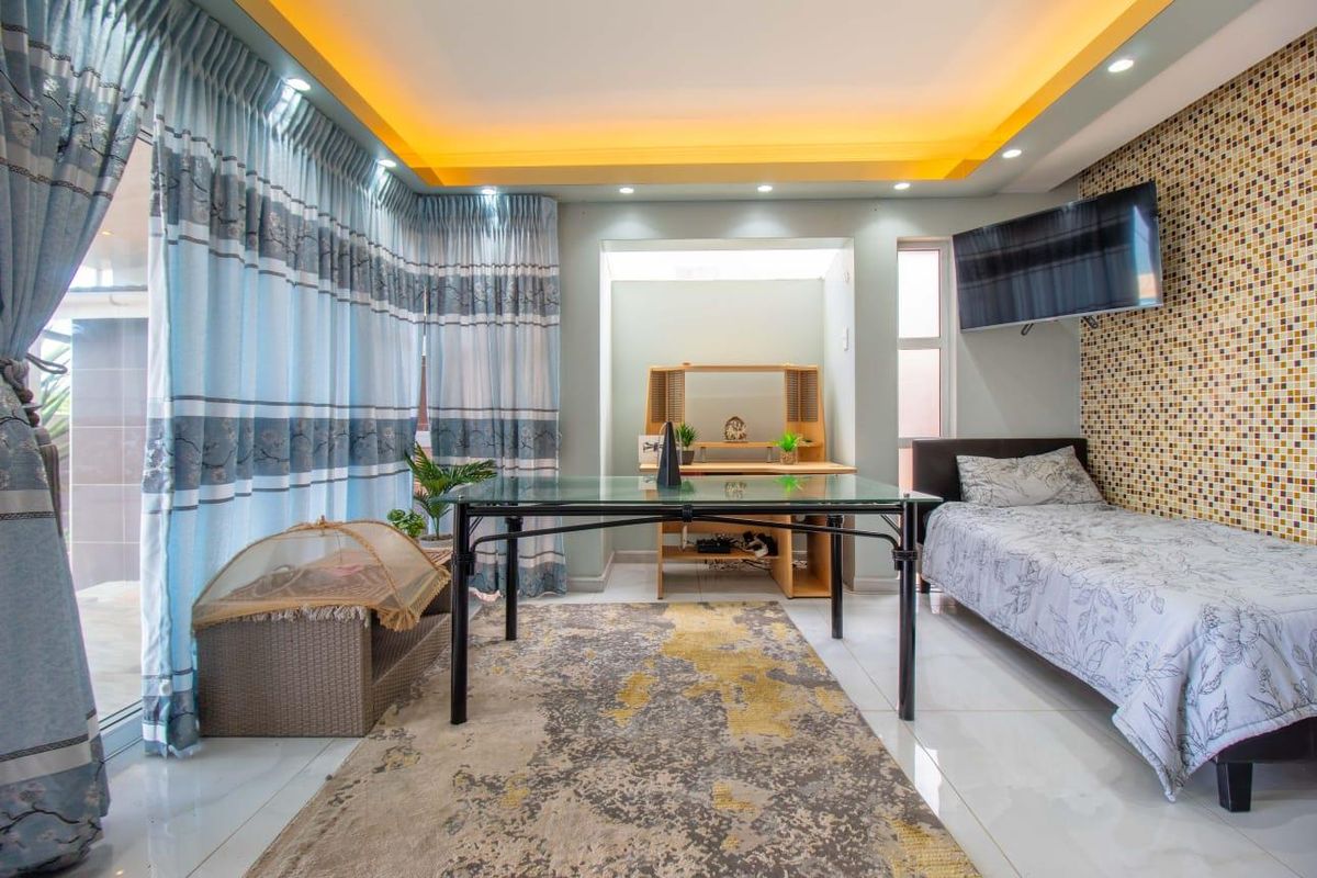 A well-lit bedroom featuring a mosaic tile accent wall, recessed ceiling lighting, and large sliding glass doors providing access to the exterior.
