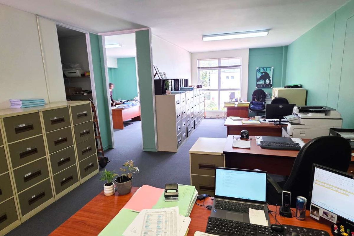 A functional office space featuring partition walls, carpet flooring, and overhead fluorescent lighting, providing a practical layout for a professional work environment.
