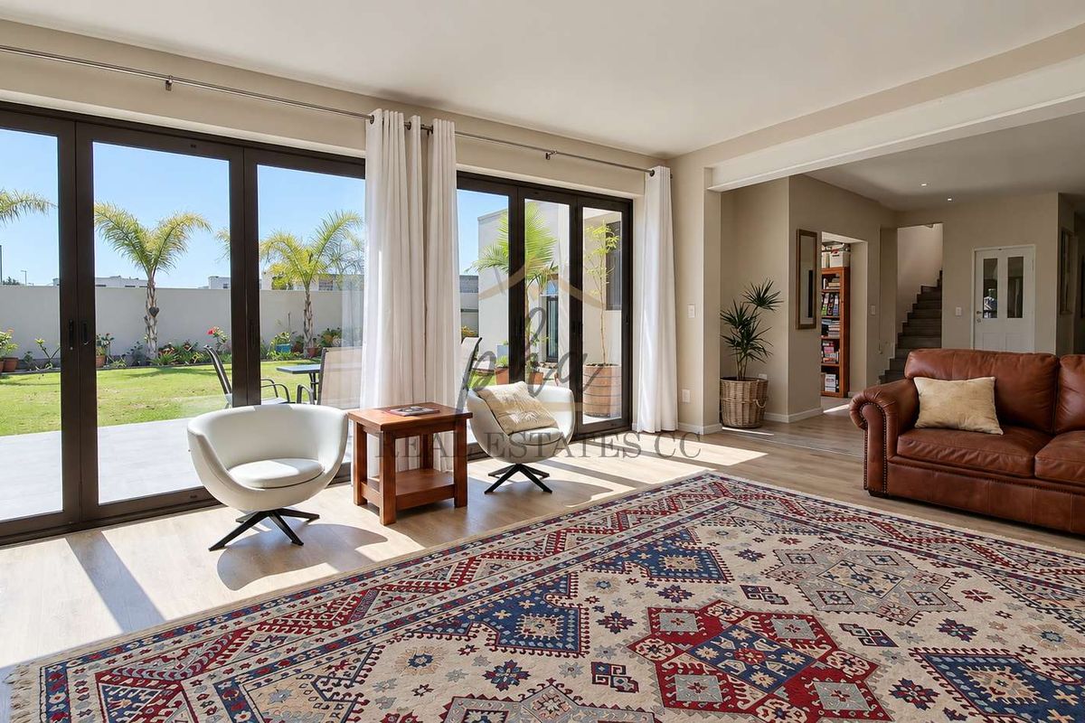 Spacious living area featuring large aluminium sliding doors that provide seamless access to the garden, complemented by modern laminate flooring and recessed lighting.