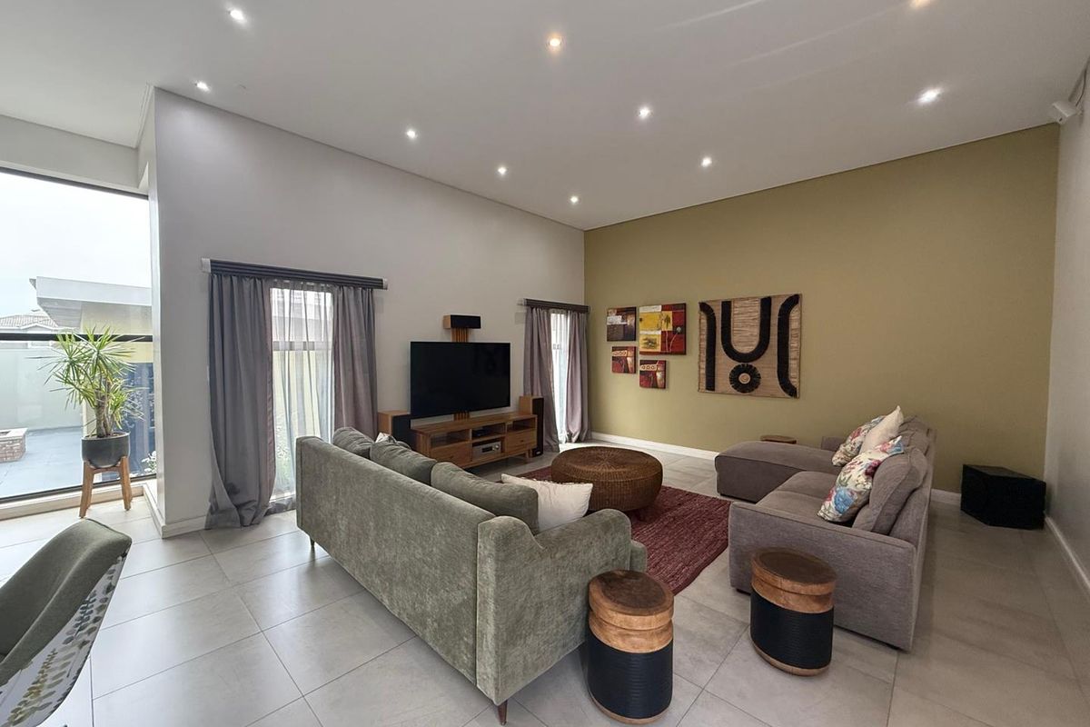 Spacious living room featuring large format floor tiles, recessed downlighting, and expansive windows that provide ample natural light.