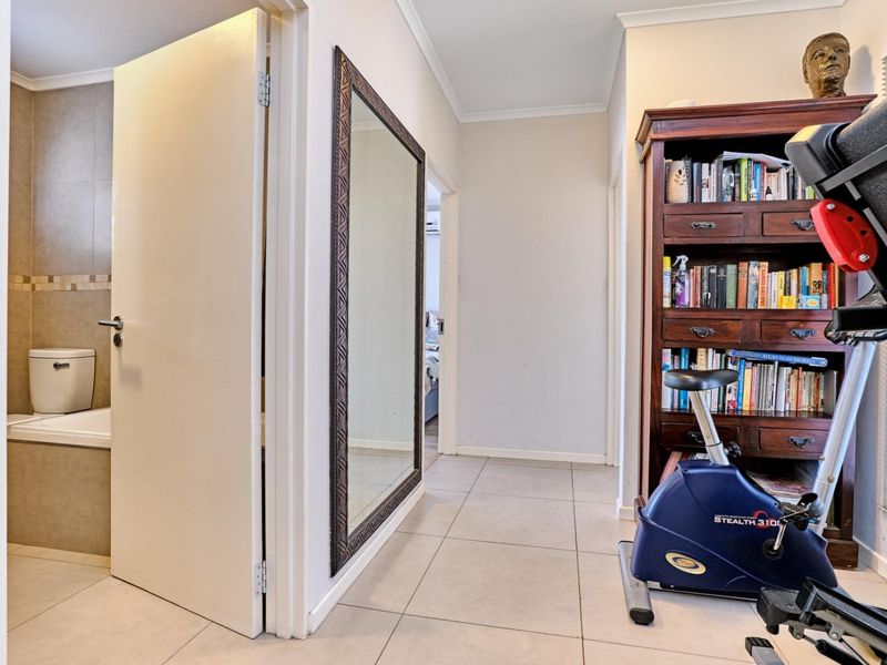 A tiled hallway providing access to a bathroom and adjacent rooms, featuring neutral wall finishes and standard internal door frames.