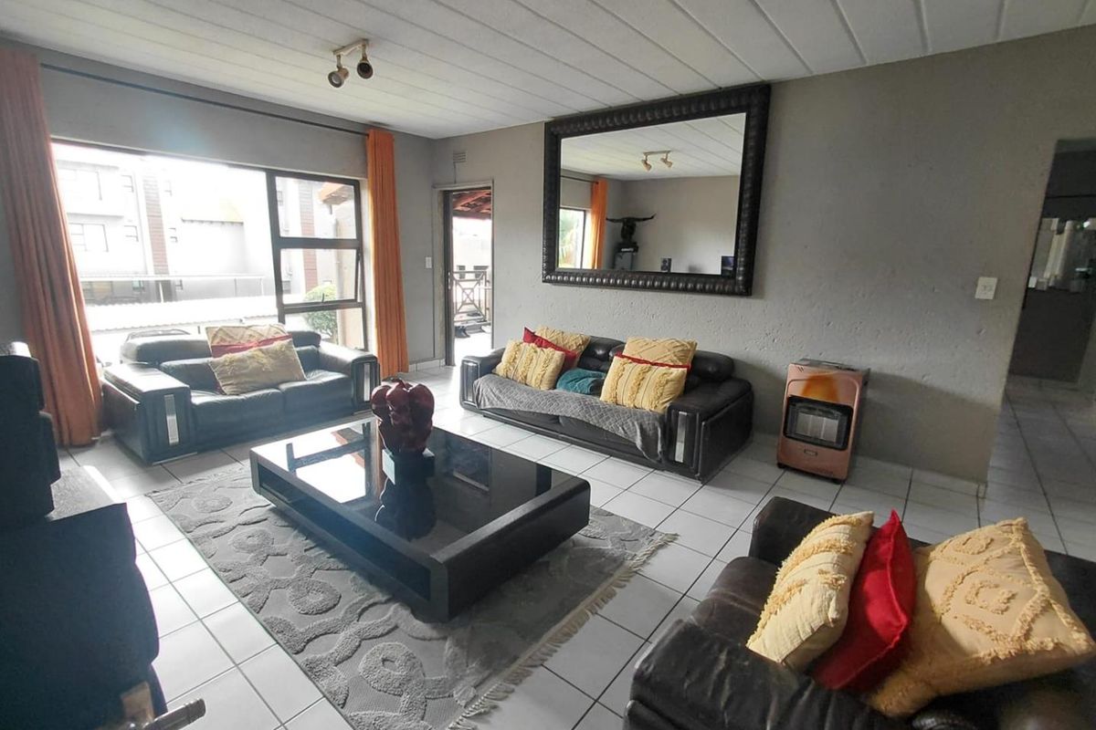 Spacious living room featuring large windows, tiled flooring, and a built-in gas heater, offering a comfortable and functional layout.