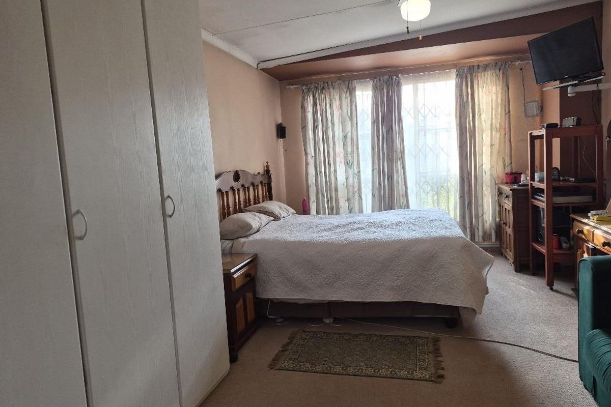 A bedroom featuring built-in cupboards, carpeted flooring, and a ceiling fan, with access to a secure window area.