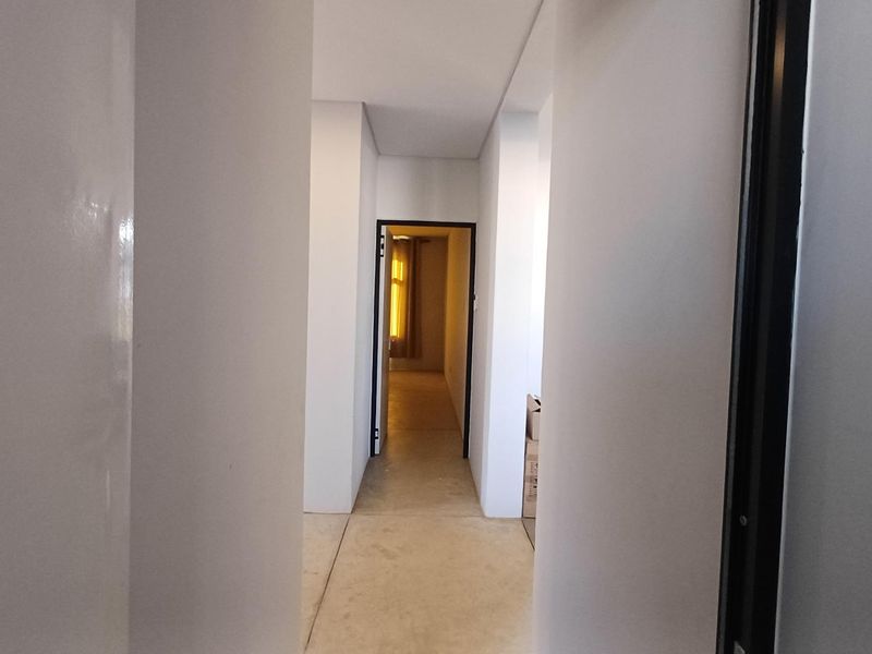 A clean, neutral hallway connecting interior spaces, featuring tiled flooring and simple door frames.