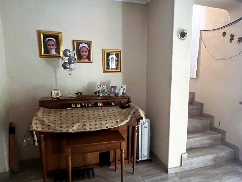 A living area featuring tiled flooring and a staircase leading to an upper level.