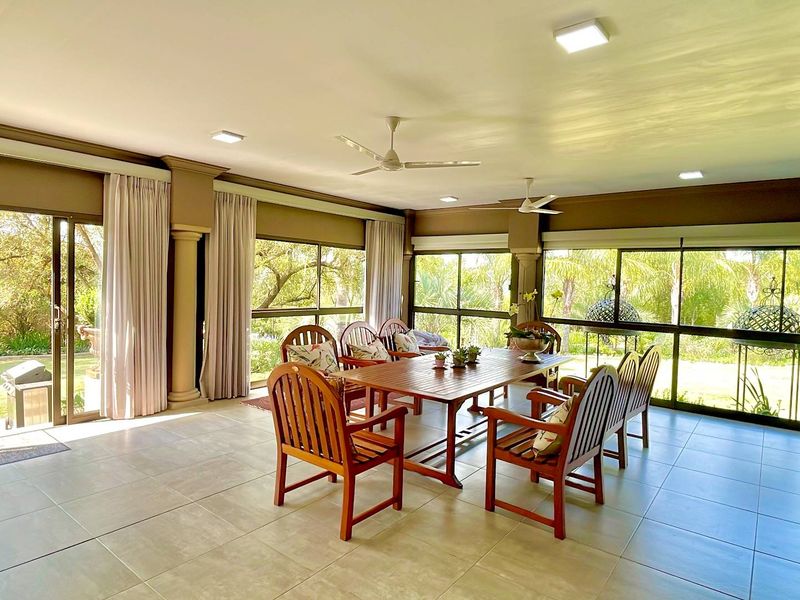 Spacious covered patio featuring tiled flooring, ceiling fans, and large sliding glass doors that provide seamless access to the garden.