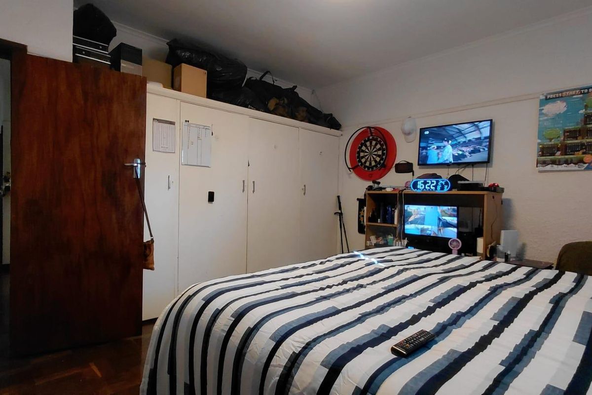 A bedroom featuring built-in cupboards and parquet flooring, providing functional storage and classic flooring finishes.