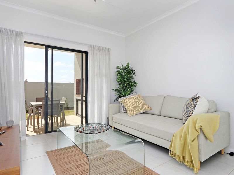 Bright living room featuring tiled flooring and a large sliding glass door providing direct access to an outdoor patio area.
