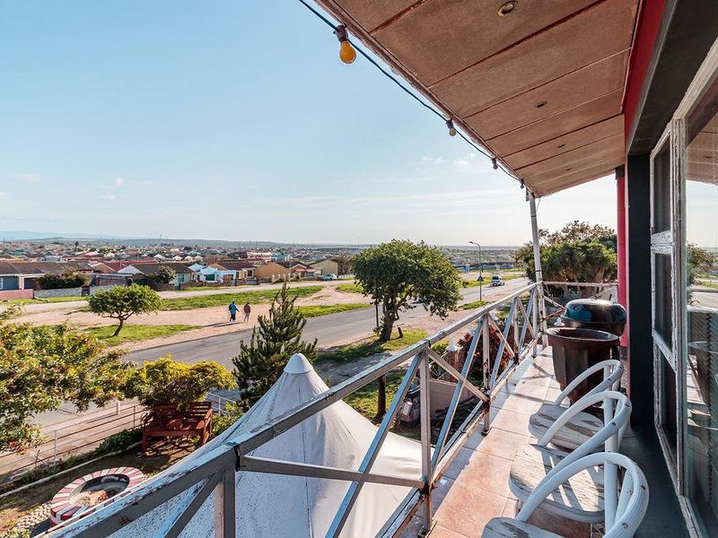 An elevated balcony featuring tiled flooring and a metal balustrade, offering expansive neighbourhood views and a covered outdoor space.