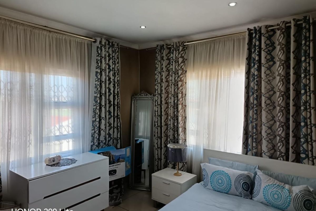 A bedroom featuring tiled flooring, recessed downlights, and windows fitted with security bars, offering a functional living space.