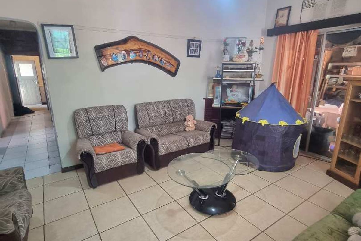 A living room featuring tiled flooring and access to an adjacent hallway, providing a functional and open living space.