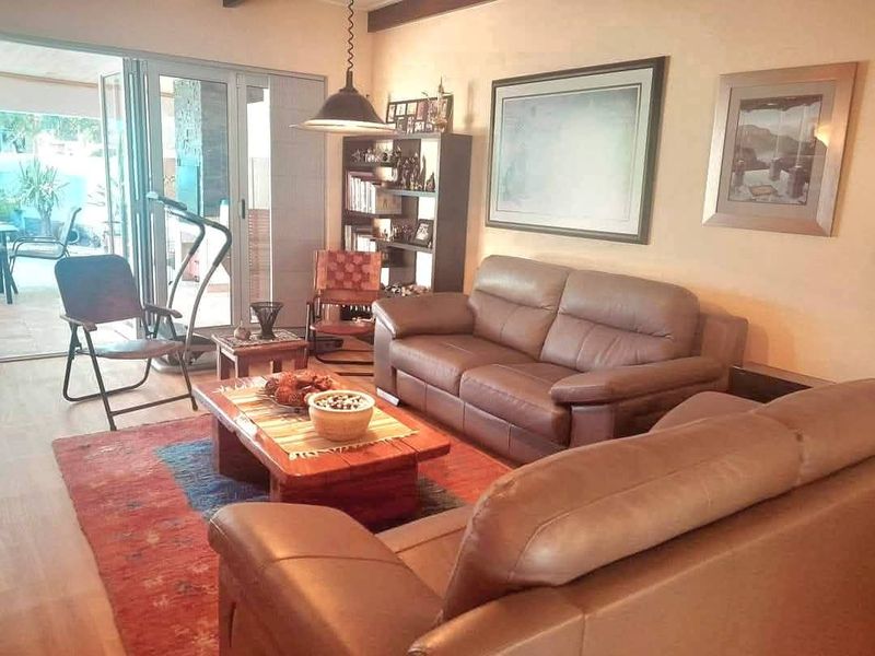 A comfortable living room featuring exposed timber ceiling beams and large aluminium stacker doors providing seamless access to the outdoor patio area.