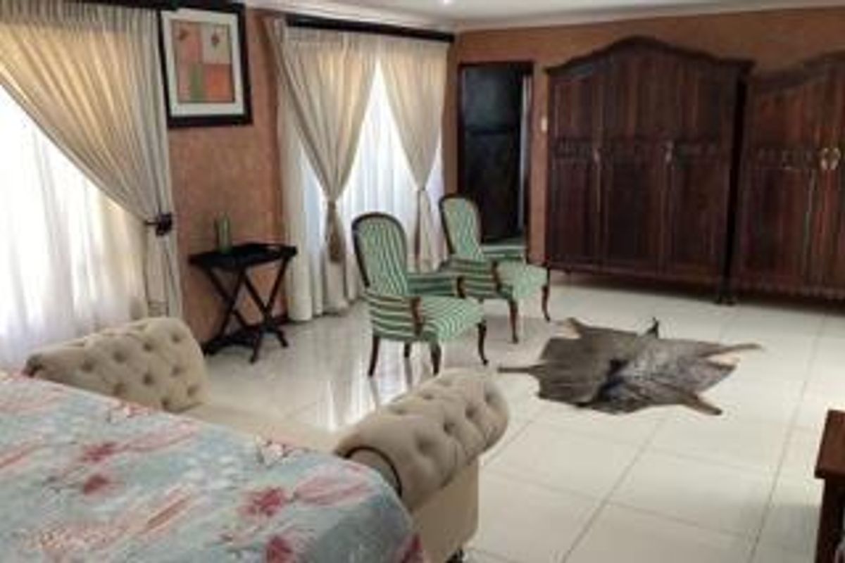 Spacious bedroom featuring tiled flooring, large windows with curtains, and built-in wooden cabinetry.