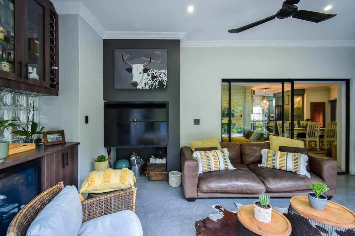 A cozy living area featuring a built-in fireplace, dark cabinetry, and a ceiling fan, with sliding glass doors leading to an adjacent dining space.