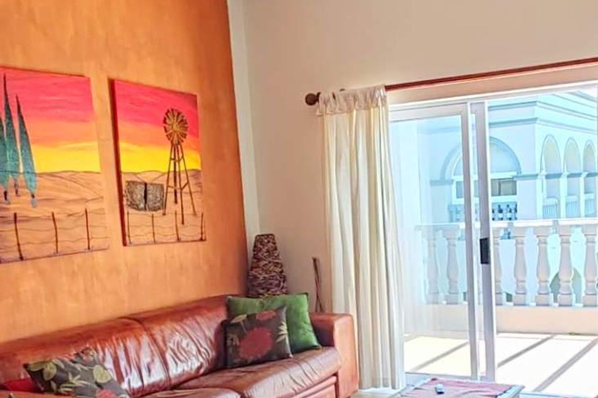 Living room featuring a textured accent wall and sliding glass doors that open onto a balcony with balustrade detailing.