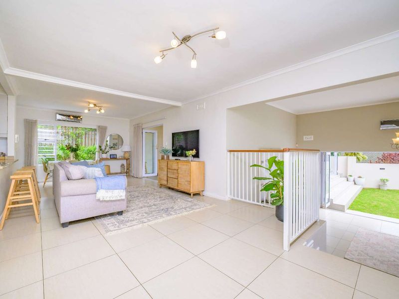 Spacious open-plan living area featuring neutral tiled flooring, split system air conditioning, and direct access to an outdoor patio and garden space.