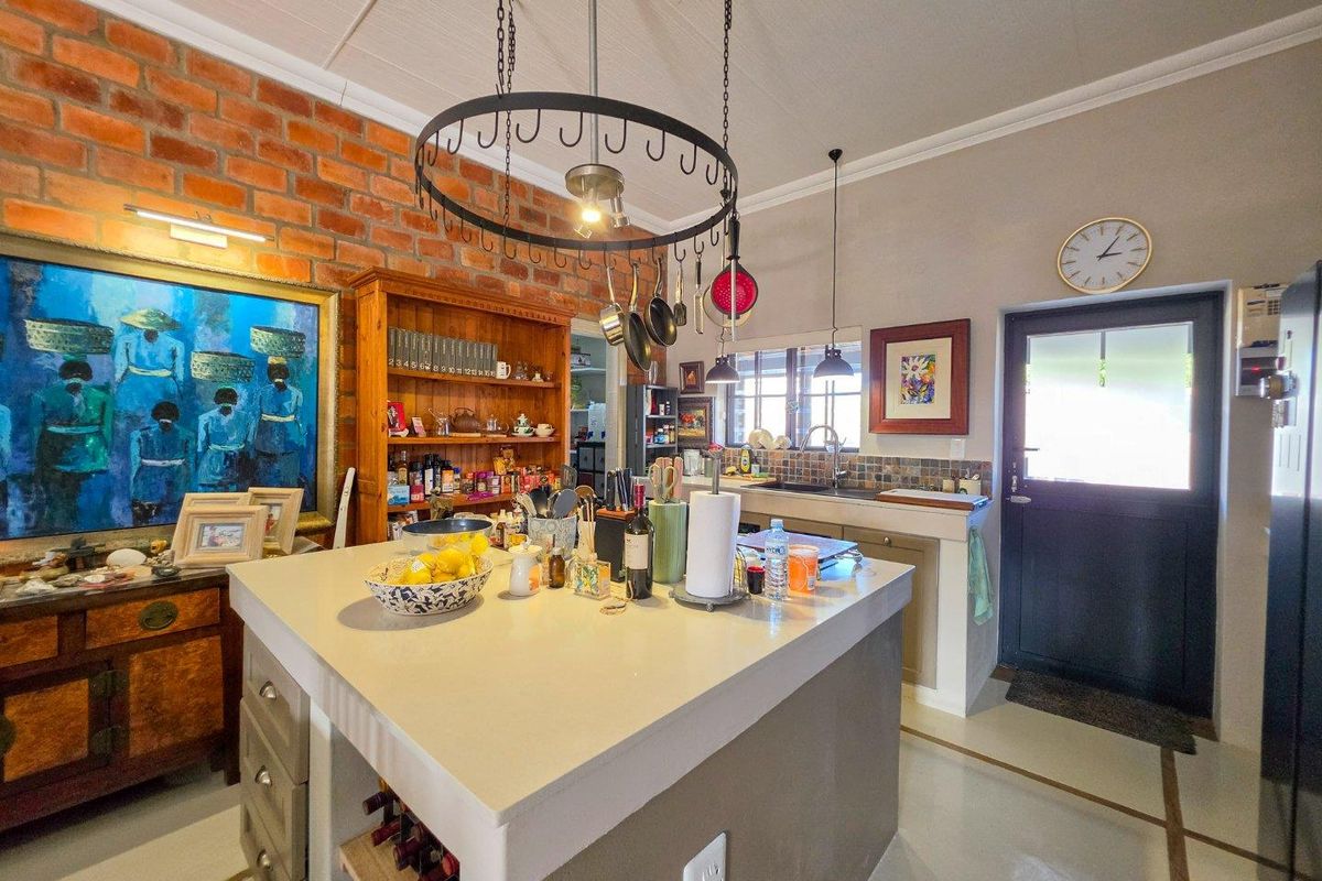 A characterful kitchen featuring a central island, exposed brick wall, hanging pot rack, and direct access to the exterior.