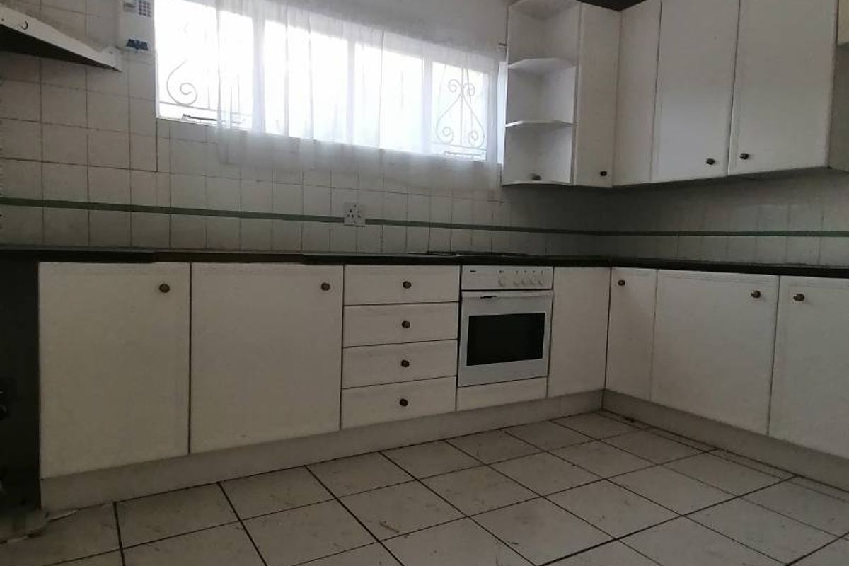 A functional kitchen featuring white built-in cabinetry, tiled flooring, and a built-in oven, offering a blank canvas for potential renovation and modernization.