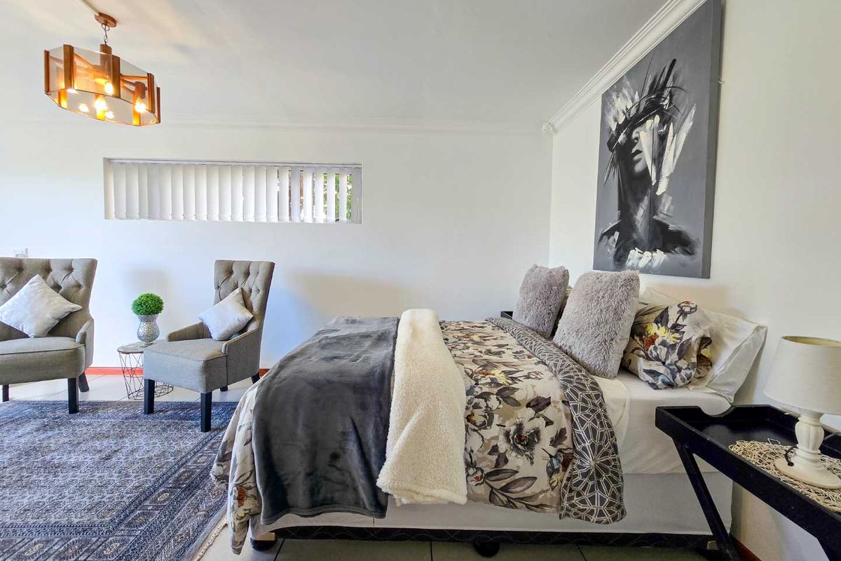 A well-lit bedroom featuring tiled flooring, a modern pendant light fixture, and a horizontal clerestory window.