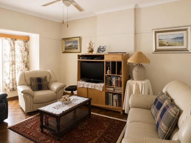 A comfortable living room featuring parquet flooring, a ceiling fan, and classic coving detail.