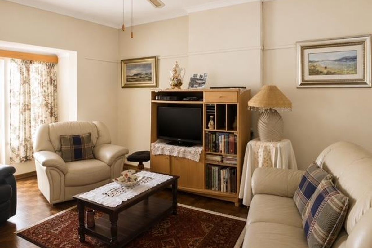 A comfortable living room featuring parquet flooring, a ceiling fan, and classic coving detail.