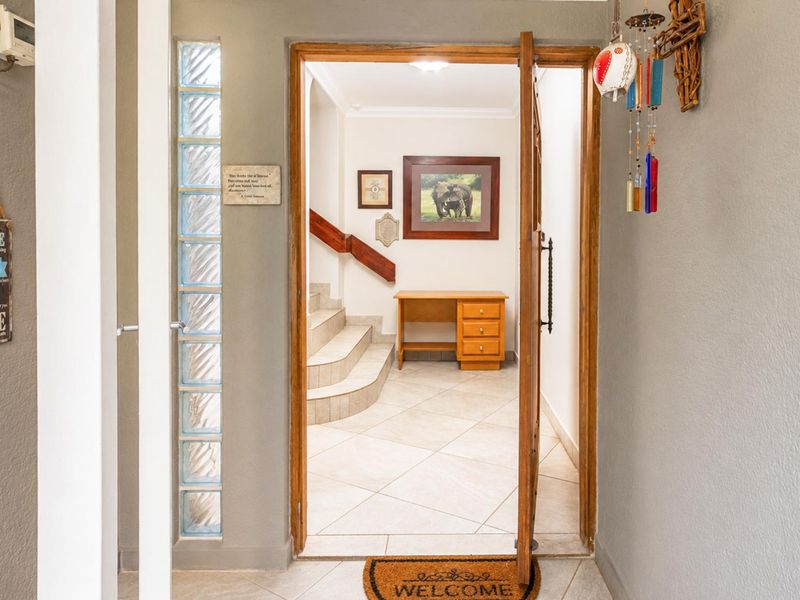 A welcoming entrance hall featuring tiled flooring, a decorative glass block wall, and a staircase with a wooden handrail leading to the upper level.