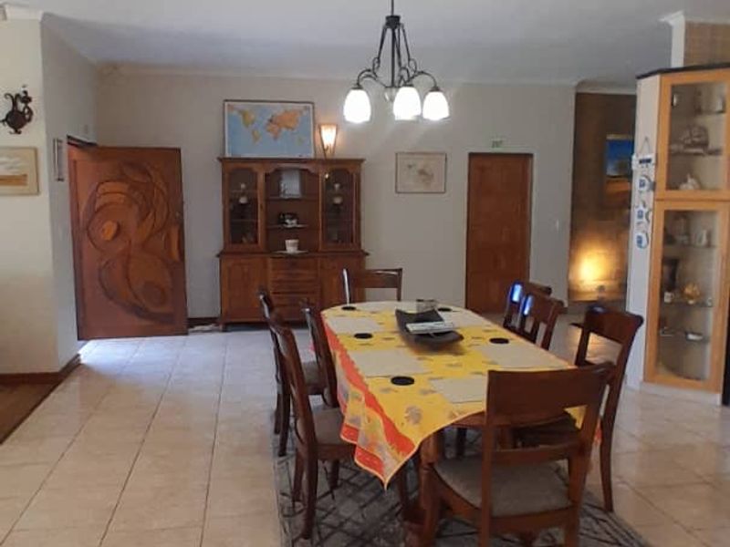 A spacious dining area featuring neutral tiled flooring and a central pendant light fixture, providing a functional space for family meals.