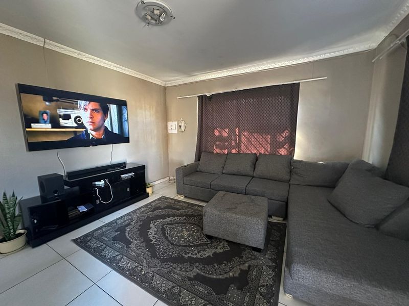 A comfortable living room featuring tiled flooring and decorative ceiling cornicing, providing a functional space for relaxation and entertainment.