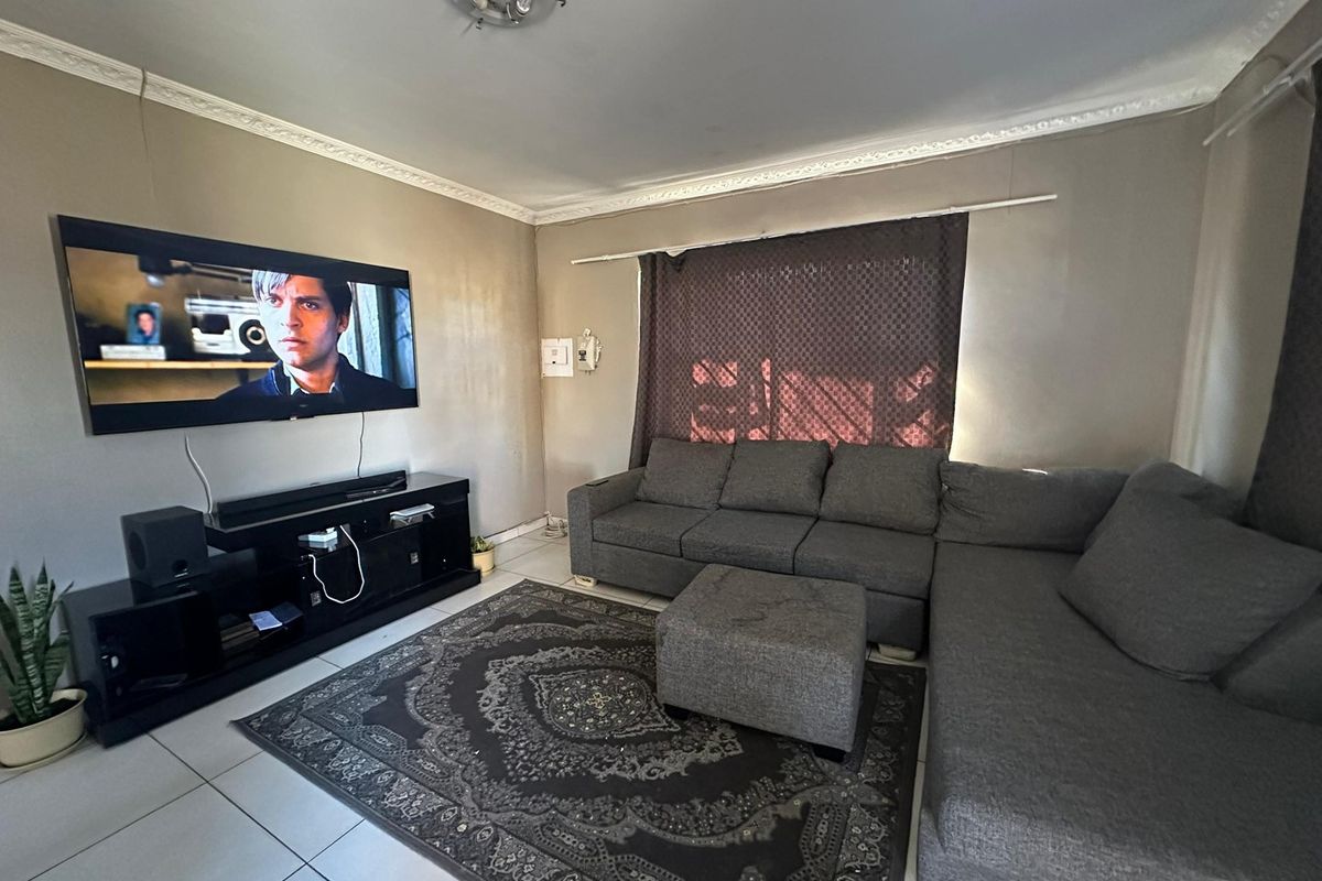 A comfortable living room featuring tiled flooring and decorative ceiling cornicing, providing a functional space for relaxation and entertainment.