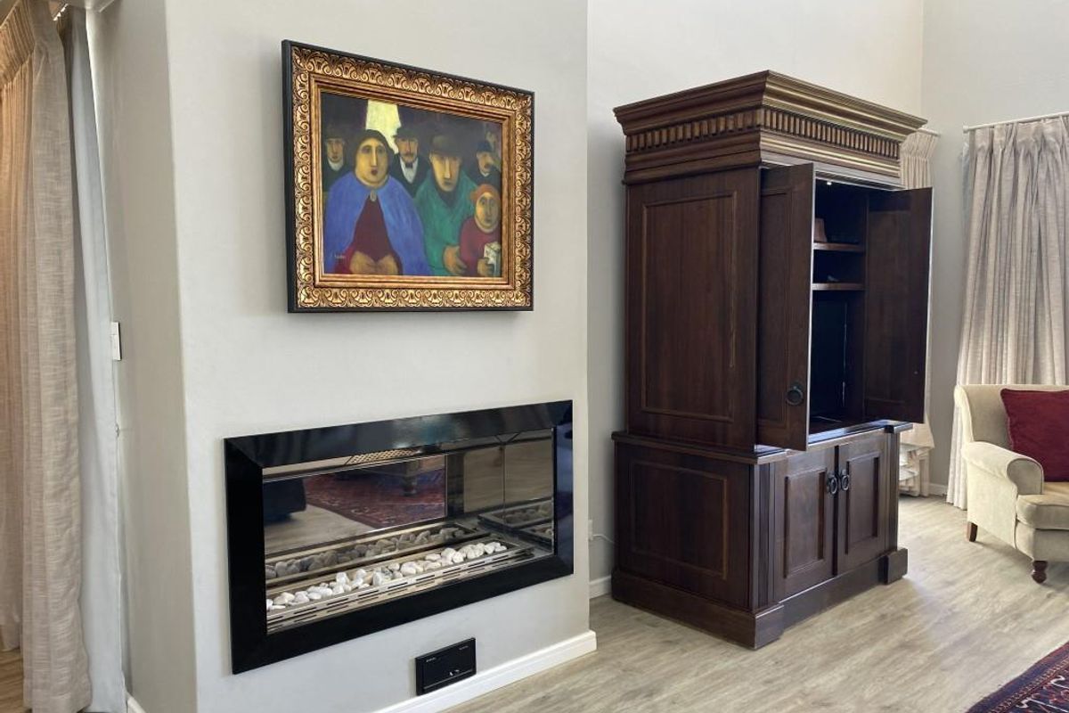 A well-maintained living room featuring a modern built-in fireplace with a sleek black frame and light-toned wood-look flooring.