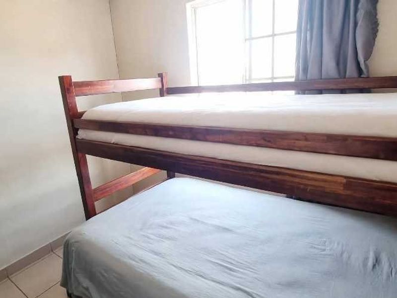 A compact bedroom featuring tiled flooring and a window, currently furnished with a bunk bed.