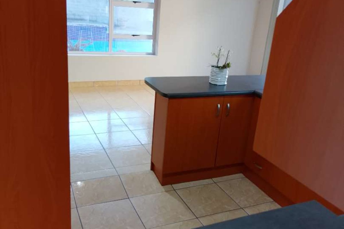 A functional kitchen area featuring laminate cabinetry, dark countertops, and ceramic floor tiles, offering a clean and neutral space ready for personalization.