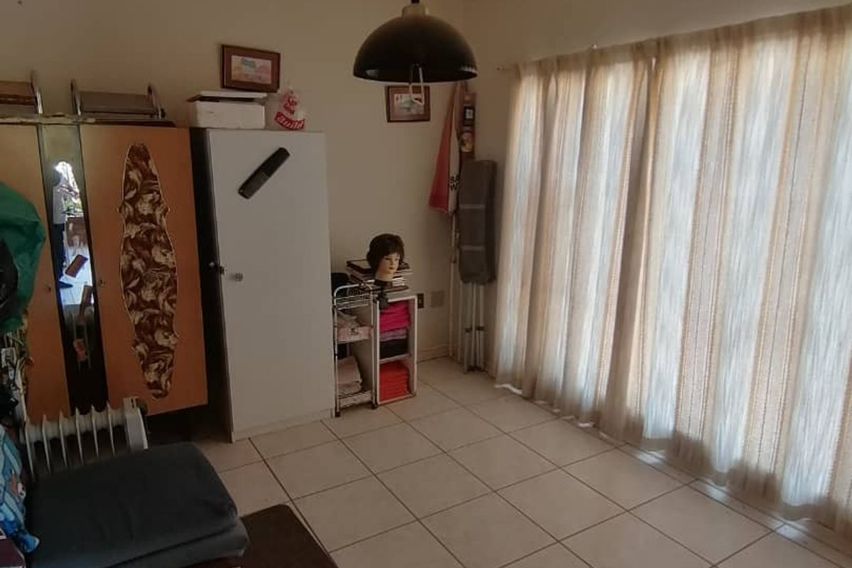 A living area featuring tiled flooring and large sliding glass doors with curtains, providing access to the exterior.