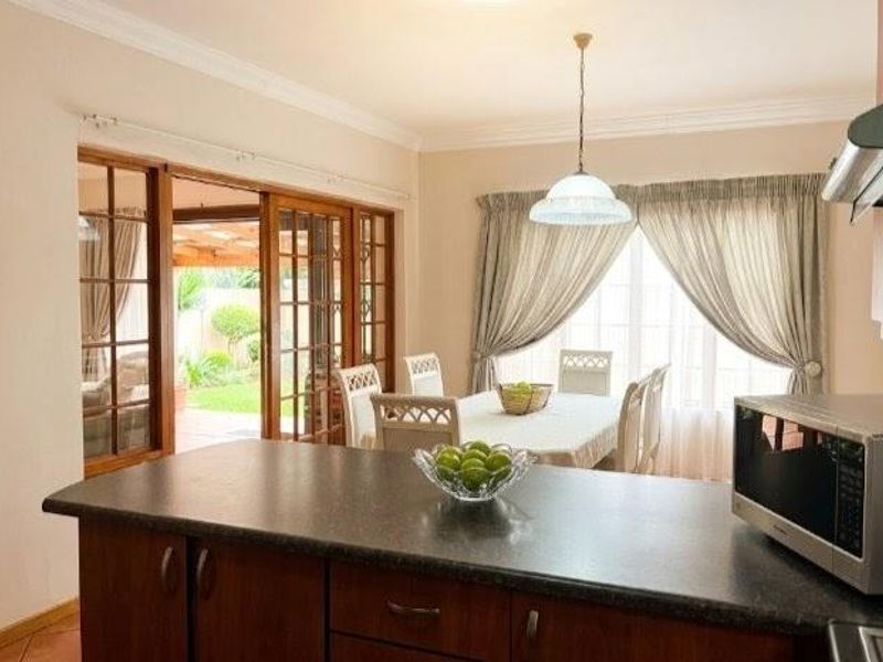 Open plan kitchen and dining area featuring wooden cabinetry, dark countertops, and sliding glass doors providing direct access to the garden patio.