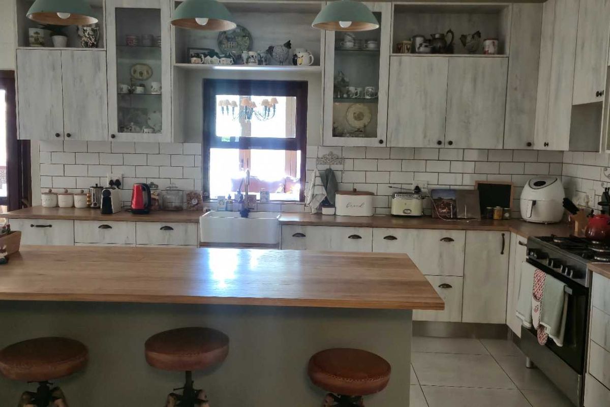 A farmhouse-style kitchen featuring white cabinetry, a wooden island countertop, a farmhouse sink, subway tile backsplash, and a built-in gas stove.